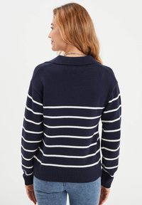 Navyblauw gebreid sweater met witte horizontale strepen. Het heeft een geribde onderkant en manchetten, en een ontspannen pasvorm met een kraagontwerp.