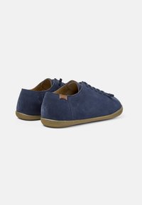 Navy suede casual shoes with a low profile, round toe, and rubber sole. Features a lace-up design and a small brand tag on the heel.
