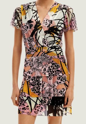 Femme portant une robe à manches courtes, col en V, jupe à volants et motif floral abstrait coloré en rose, jaune, noir et blanc.
