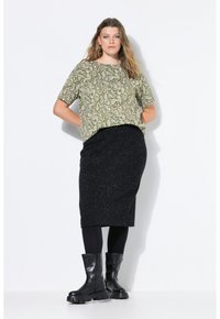 Olivgrünes Kurzarmoberteil mit Paisleymuster, kombiniert mit einem schwarzen, gepunkteten Midirock. Schwarze Stiefeletten runden das Outfit ab.