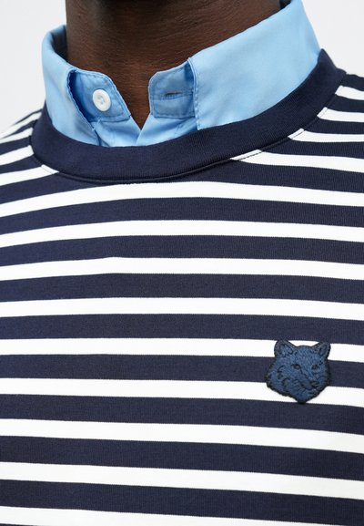 Navy and white striped polo with a light blue collar. Features an embroidered blue fox logo on the left chest area and ribbed collar.
