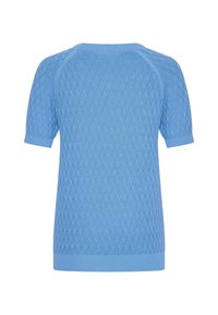 Vaaleansininen neulottu lyhythihainen neuletakki, jossa on teksturoitu timanttikuvio, resorit kaula-aukossa ja hihansuissa. Takana näkyy saumatonta raglan-mallia.