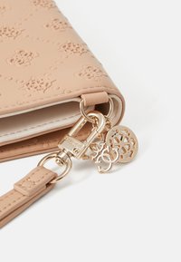 Light pink wallet made of textured material, featuring embossed floral patterns, gold hardware, and decorative charms.