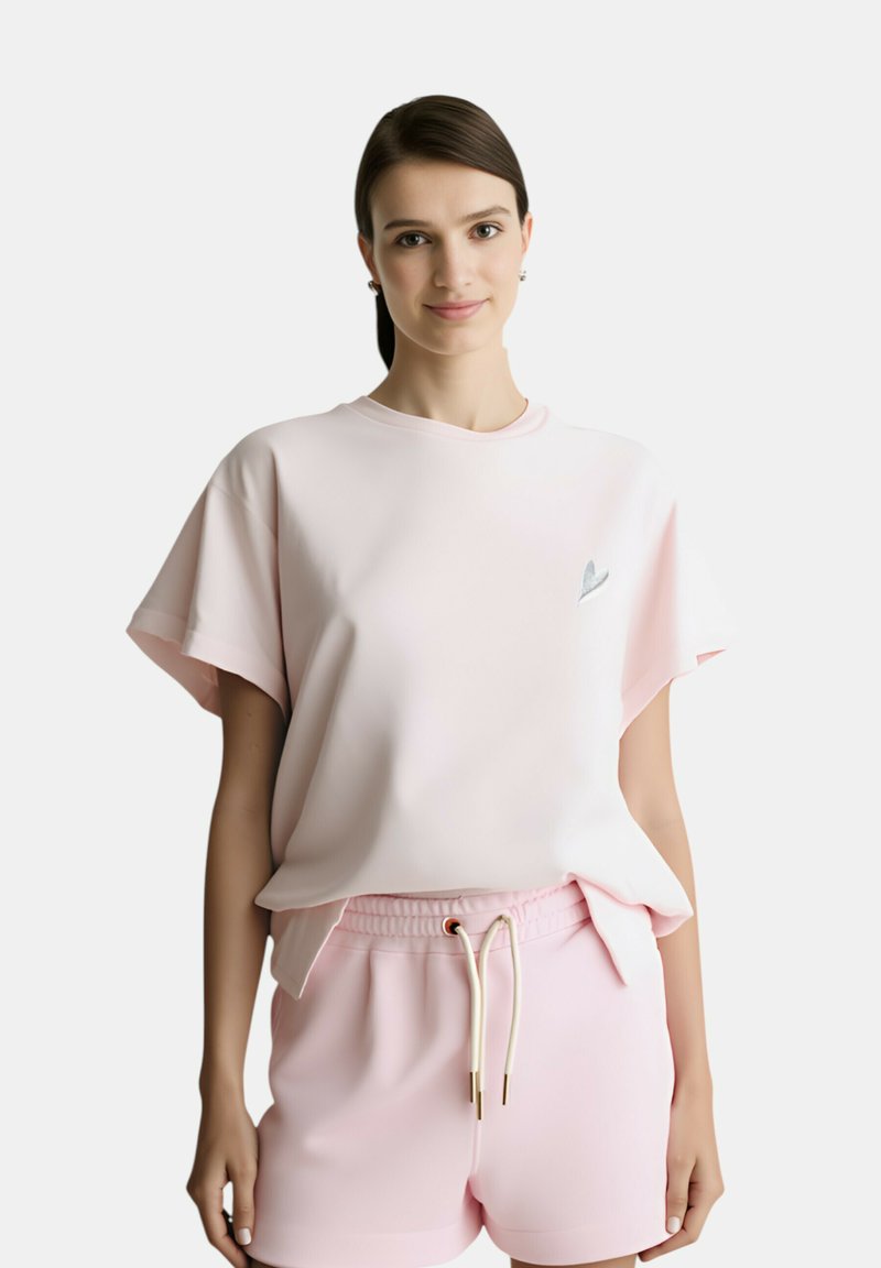 T-shirt in cotone rosa chiaro con maniche corte, scollo a girocollo e piccolo logo a cuore argentato. Abbinato a pantaloni corti rosa con coulisse.