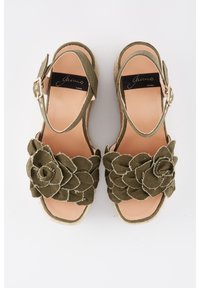 Paire de sandales vert olive à bout ouvert avec brides à la cheville et grandes fleurs en tissu en guise d'ornements sur les brides avant, semelles plates en espadrille.