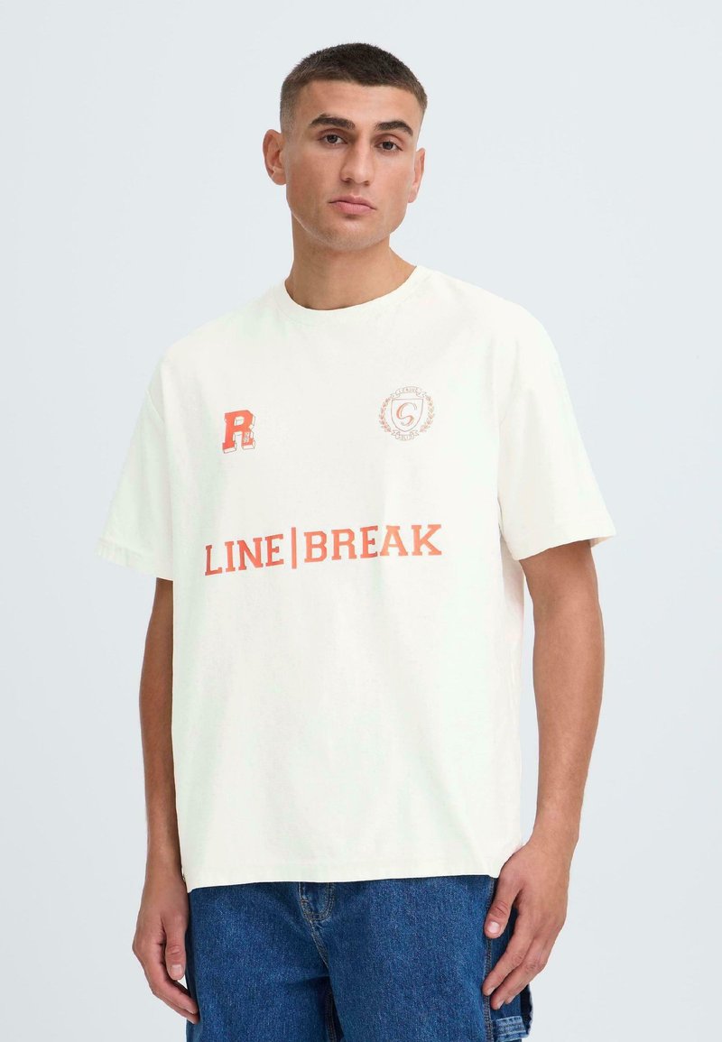 Lyscremet bomulds t-shirt med korte ærmer, der har rødt trykt tekst: "R" logo på øverste venstre og "LINE|BREAK" tværs over brystet.