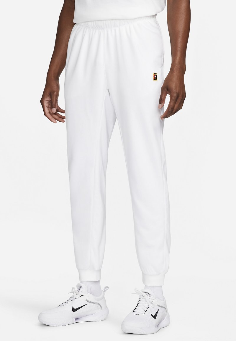 Pantalon de jogging blanc avec une ceinture élastique, des poignets et un petit logo multicolore sur la cuisse gauche. Confectionné dans un tissu lisse.