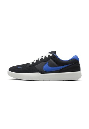 Zapatilla Nike baja de color negro y azul con cordones blancos y suela de goma blanca, mostrada de lado sobre un fondo blanco.