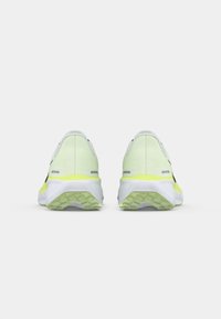 Baskets de course blanches et jaunes fluo avec une tige en maille texturée, des accents noirs et une semelle extérieure en caoutchouc à motif.