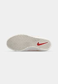 Semelle de chaussure avec un motif géométrique répétitif et un logo Nike swoosh rouge près du talon sur fond blanc.
