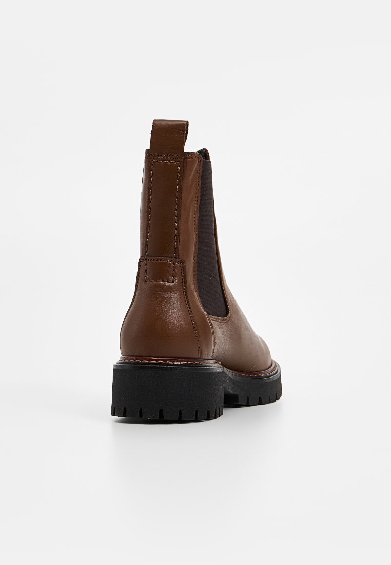 Braune Leder Chelsea-Stiefel mit elastischen Seiteneinsätzen, einer strukturierten schwarzen Gummisohle und genähten Akzenten entlang der Ränder. Rückansicht dargestellt.