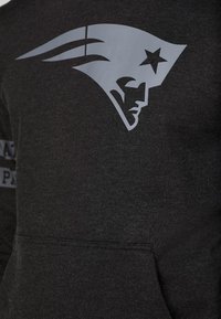 Sweat-shirt gris foncé avec un grand logo des New England Patriots, présentant une tête de patriote stylisée avec une étoile sur le chapeau.