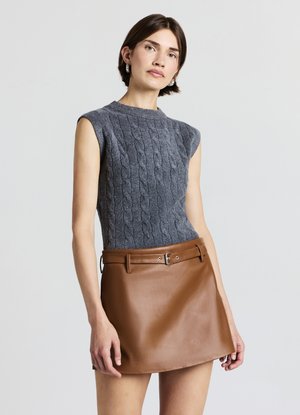 Graues, gestricktes ärmelloses Oberteil mit Zopfmuster, kombiniert mit einem glatten braunen Leder-Minirock mit Gürtel- und Schnallendetail.