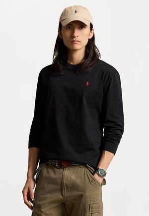 Black long-sleeve shirt with red logo on the chest, beige cap, olive green cargo pants, and a silver watch with a green dial.