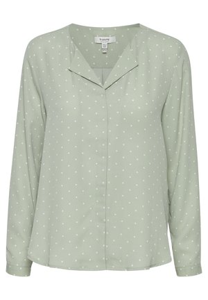 Bluză verde deschis, dintr-un material moale, cu decolteu în V, mâneci lungi și puncte albe pe o textură netedă.
