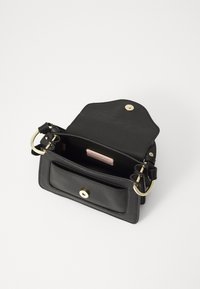Sac à main en cuir noir avec quincaillerie dorée. Doté d'une fermeture à rabat, d'une poche intérieure et d'une bandoulière réglable. Extérieur en cuir texturé.