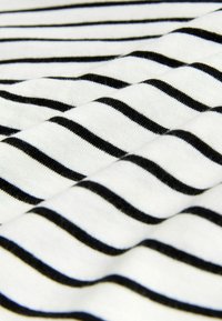 Melnbaltas svītrainas audums, kas izceļas ar mīkstu kokvilnas faktūru un vienveidīgi izvietotām horizontālām līnijām. Svītras ir vienmērīgas platumā.