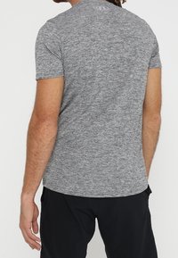 Kortärmad, melerad grå tränings-T-shirt med rund halsringning och en subtil logotyp på baksidan, tillverkad av lätt och andas material.