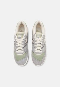 Gray suede and mesh sneakers with light green accents, cream laces, and a prominent 'N' logo on the side. Flat rubber sole visible.