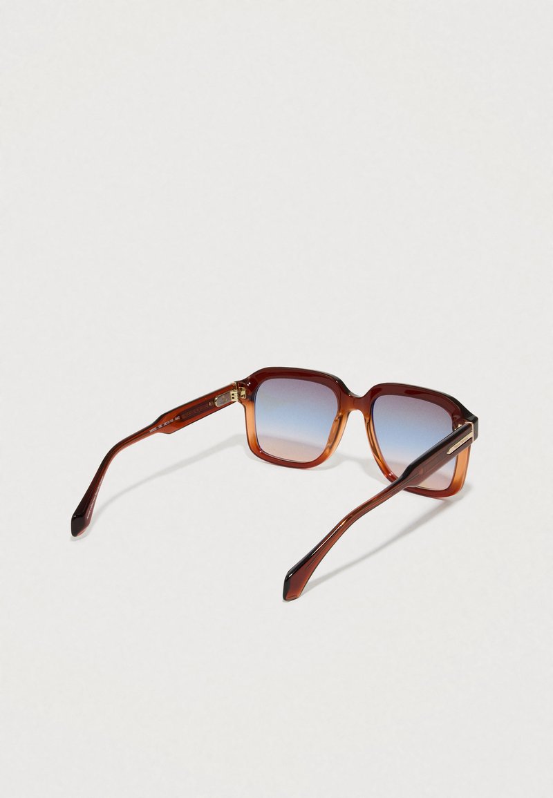 Lunettes de soleil dégradées brunes avec une monture carrée, texture lisse et branches fines. Présentent des accents dorés subtils sur les tempes.