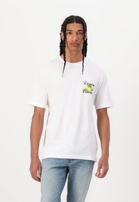 Hvid kortærmet t-shirt med et grønt og gult citrongrafik og teksten "Limón Citrón", lavet af blødt bomuldsstof. Casual pasform.