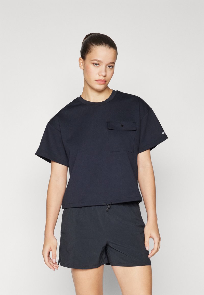 Marinblå croppad T-shirt med korta ärmar, med en framficka och rundad halsringning. Kombinerad med svarta shorts. Slätt tyg, avslappnad passform.