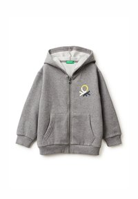 Sudadera gris con cremallera, hecha de tela suave, que presenta un diseño de logo frontal en amarillo, azul marino y crema. Incluye bolsillos frontales y capucha.