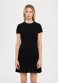 Melnā kleita ar teksturētu augšdaļu, īsām piedurknēm un viļņotu apakšmalu. Izgatavota no austu audumu, tai ir pieguļošs siluets.