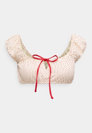 Bikini top met pofmouwen, crèmekleurige stof met rode stippen en een rode striksluiting aan de voorkant. Glad van textuur, met geplooid ontwerp.