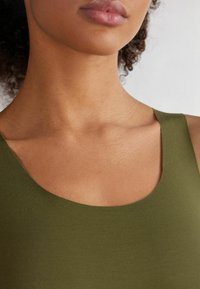Olivově zelený top na ramínka s širokým kulatým výstřihem, vyrobený z hladkého materiálu. Vyznačuje se přiléhavým střihem, který zvýrazňuje texturu pleti pod ním.