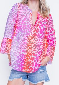 Blusa con stampa animalier colorata caratterizzata da tonalità di rosa, arancione e viola, con una vestibilità ampia, scollatura a v e maniche a campana realizzate in tessuto leggero.