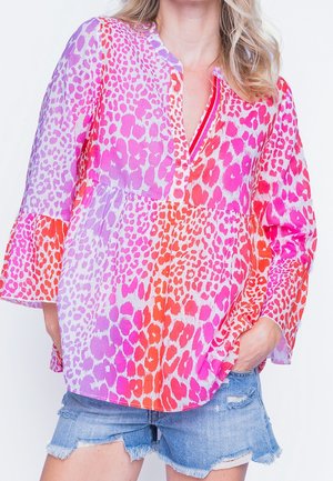 Blusa con stampa animalier colorata caratterizzata da tonalità di rosa, arancione e viola, con una vestibilità ampia, scollatura a v e maniche a campana realizzate in tessuto leggero.