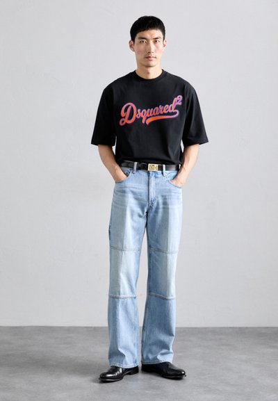 Tricou negru cu mânecă scurtă și logo roșu "Dsquared²", combinat cu blugi din denim bleu deschis cu un design patchwork și pantofi din piele negri.