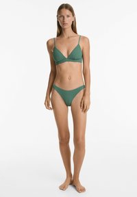Zelený bikiny set s texturovaným povrchem; trojúhelníková braletka s tenkými ramínky a odpovídající nízké kalhotky. Vhodné na plavání.
