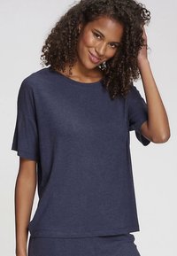 Tumši zils ribots īsroku tops ar vaļēju piegriezumu un apaļu izgriezumu, ar smalku tekstūru un nedaudz garāku aizmugures malu.