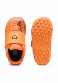 Scarpe da ginnastica di un vivace arancione con strisce rosa, suole in gomma testurizzata con motivi esagonali e una fascia in Velcro per una vestibilità sicura.