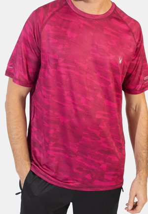 Mann trägt ein dunkelrosa Tarnmuster-Sportshirt mit kurzen Ärmeln und kleinem weißem Spinnenlogo auf der Brust.