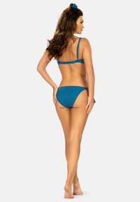 Zestaw bikini w kolorze turkusowym z teksturowanej tkaniny, z regulowanymi ramiączkami i zapięciem na klamrę z tyłu. Dolna część ma niską talię i minimalny krój.