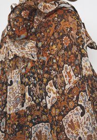 Tissu marron avec un motif floral et animalier complexe dans des tons d'orange, jaune, blanc et bleu, présentant des bords froncés.