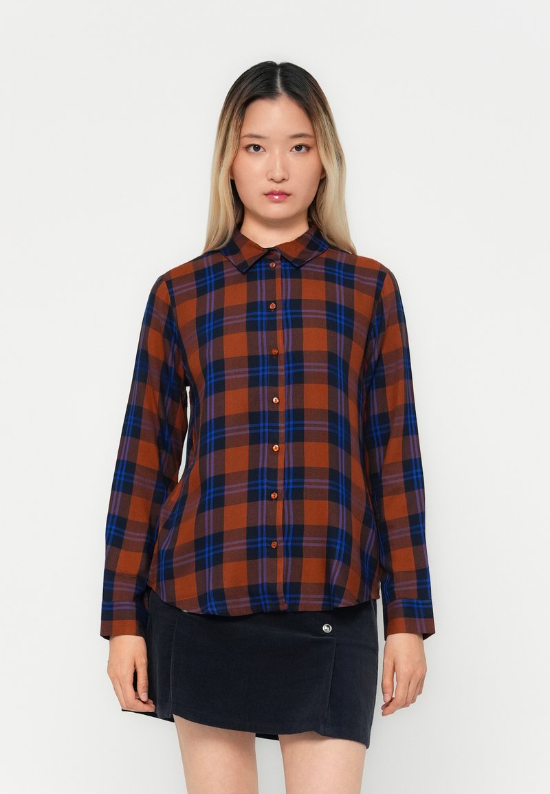 Plaid shirt in brown, blue, and orange tones, featuring a collar, button closure, and long sleeves. Textured fabric with a relaxed fit.