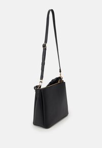 Svart läderaxelväska med en strukturerad form, justerbar rem, guldfärgade detaljer och ett blixtlåstår som öppnar upp.