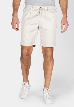Beige shorts met een koord in de taille, plooien aan de voorkant, opgerolde zoom en zijzakken, gecombineerd met witte sneakers. Gemaakt van katoen.