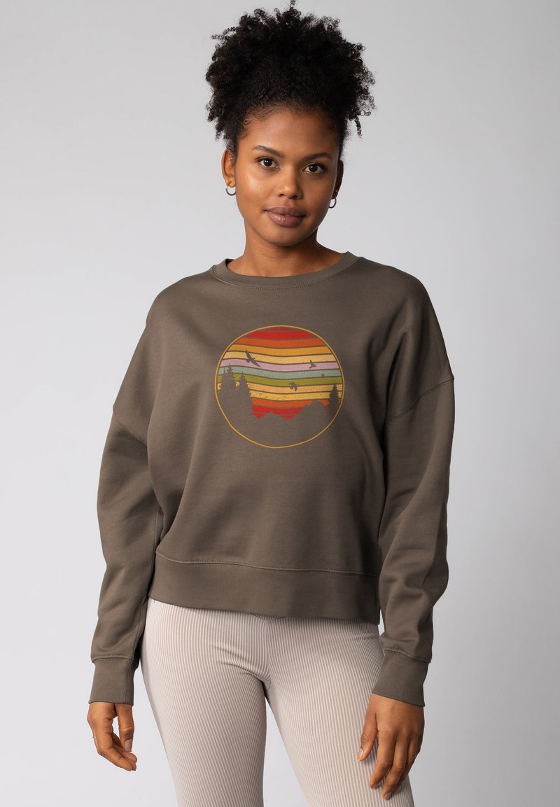 Olijfgroene sweatshirt met een ronde, veelkleurige zonsonderganggrafiek en bossilhouetten. Beschikt over een relaxed fit en ribbels aan de mouwen.