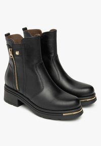 Bottes de cheville en cuir noir avec fermeture éclair, bout rond, petit talon bloc et bande dorée sur la semelle. Texture lisse dans l'ensemble.