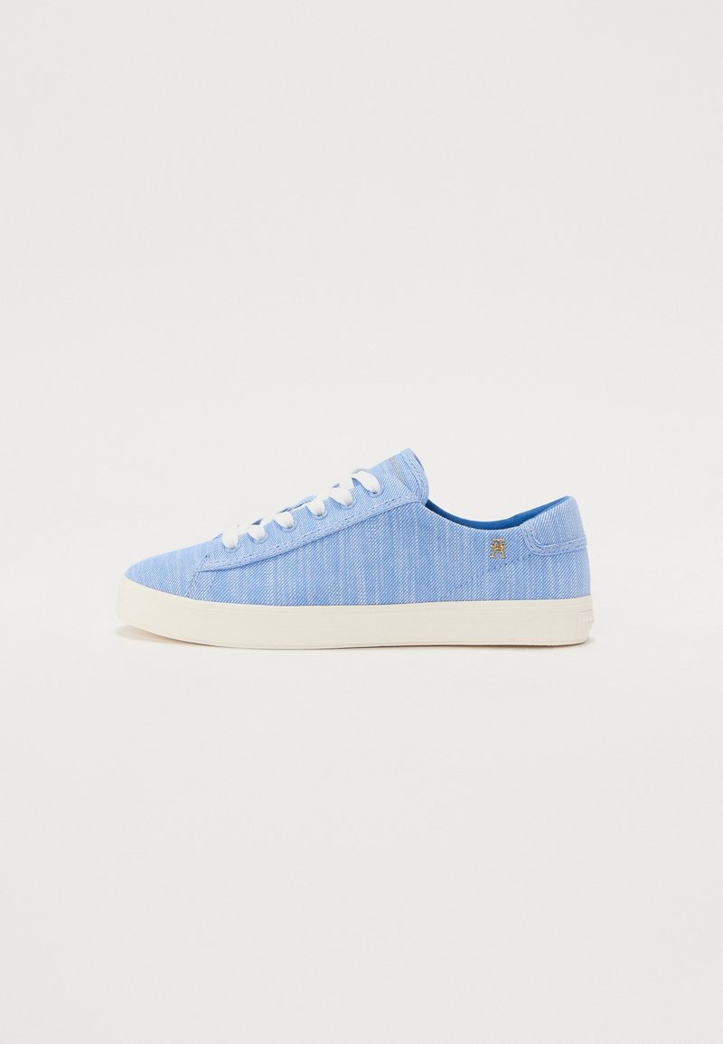 Baskets basses bleu clair avec lacets blancs et semelle blanche, vues du côté extérieur sur fond blanc uni.