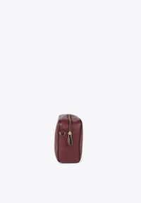 Una borsa cosmetica color bordeaux con una cerniera dorata e un'etichetta piccola, mostrata di lato su uno sfondo chiaro e semplice.