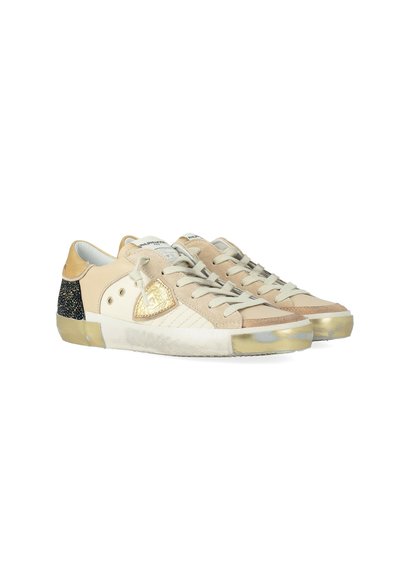 Baskets basses beige et marron clair avec des accents en daim, des lacets blancs, des détails métalliques dorés sur les côtés et les bouts, et des panneaux de talon noir moucheté.