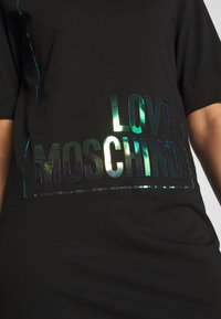 Svart t-shirt med en stor holografisk "LOVE MOSCHINO"-logotyp på framsidan, med en mjuk textur och korta ärmar.