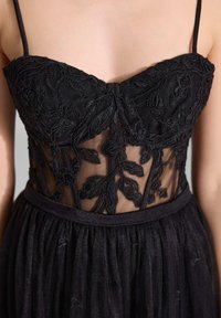 Schwarzes Kleid mit einem Oberteil aus floraler Spitzenstickerei und transparenten Netzpaneelen, ausgestattet mit dünnen Schulterträgern und einer taillierten Taille.