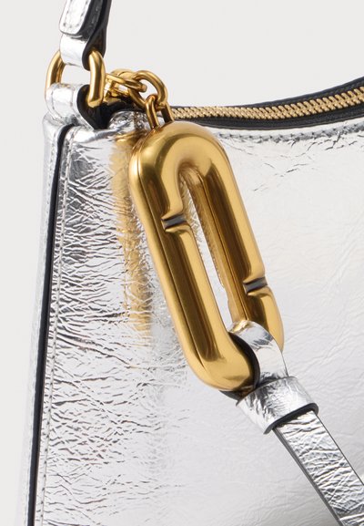 Gros plan d'un sac à main argenté texturé avec un fermoir en métal doré et une fermeture éclair, et une sangle argentée attachée au fermoir.